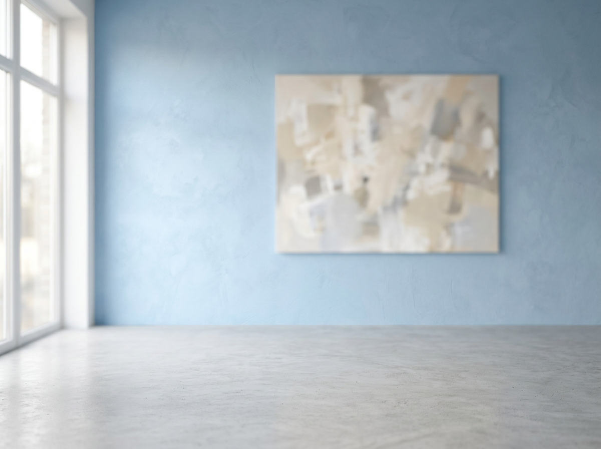 Eine leere, rauchblaue Studiowand mit weichem Lichteinfall, einem großen Fenster links und einem verschwommenen, abstrakten Gemälde mittig im Hintergrund.